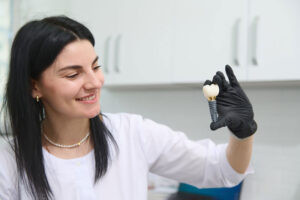 oung woman holding dental implant mockup, artificial tooth roots into jaw canal. dental treatment concept
