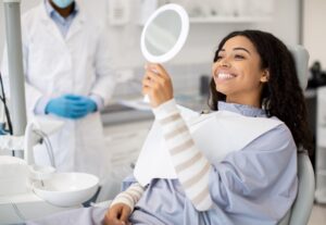 Patient holding electric and manual toothbrushes in a dental office.